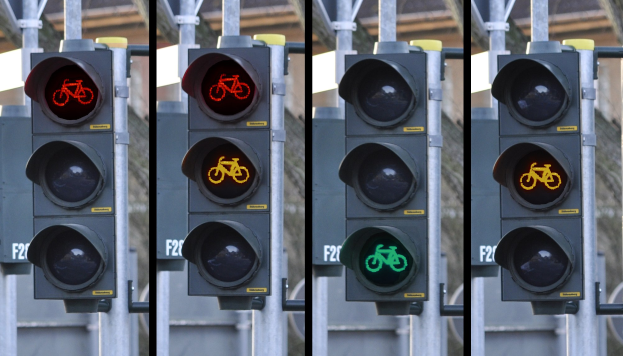 Verkehrsschild mit einem Fahrradsymbol, an einem Pfahl mit einem Gebäude im Hintergrund angebracht.