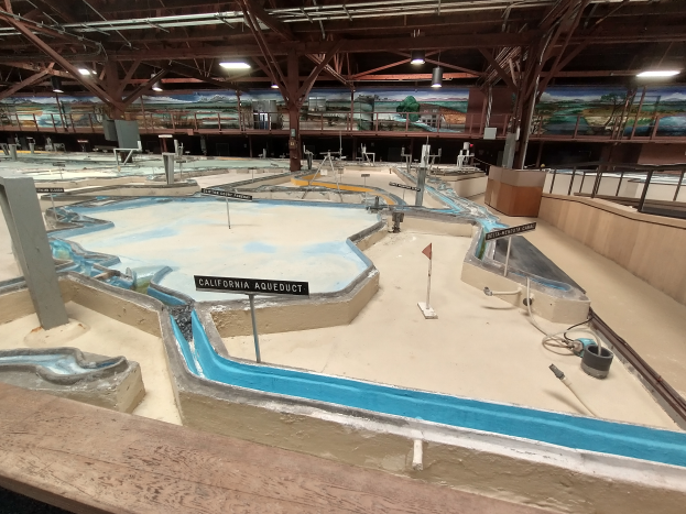 Ein großes Indoor-Wasserpark mit zahlreichen Wasserrutschen, Pfählen, Texttafeln, Deckenleuchten und Wandgemälden, das einem Minigolfplatz ähnelt und für einen spaßigen und aufregenden Erlebnis bietet.