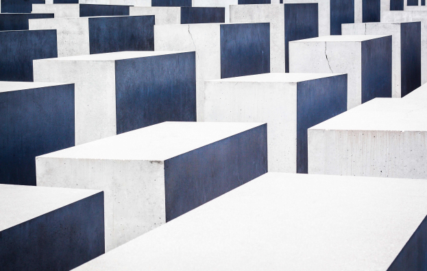 Luftaufnahme des Holocaust-Mahnmals für die ermordeten Juden Europas in Berlin, mit zahlreichen weißen und blauen rechteckigen Blöcken in einem Gittermuster angeordnet.