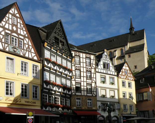 Reihe von Fachwerkhäusern in Rothenburg ob der Tauber, Deutschland, mit Fenstern, umgeben von Bäumen unter einem klaren blauen Himmel.