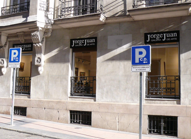 Ein mehrstöckiges Gebäude mit Fenstern, Geländern, Türen und Säulen, das Schilder an Pfosten entlang des Gehwegs und sichtbare Innenobjekte zeigt, die auf eine belebte Stadtkulisse hinweisen.