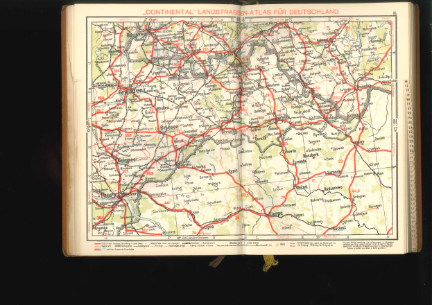 Ein aufgeschlagenes Buch mit einer detaillierten Deutschlandkarte mit Straßen und Autobahnen auf schwarzem Hintergrund.