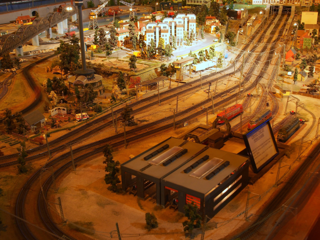 Eine detaillierte Modellbahnausstellung in einem Museum, mit einer Miniaturstadtlandschaft mit Gebäuden, Bäumen, Schienen, Fahrzeugen und anderen Gegenständen.