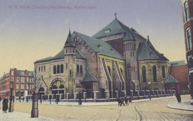 Altes Foto einer Kirche in städtischer Umgebung, umgeben von Gebäuden, Straßeninfrastruktur, Fahrzeugen, Fußgängern, Bäumen und einem klaren Himmel, mit Text oben.