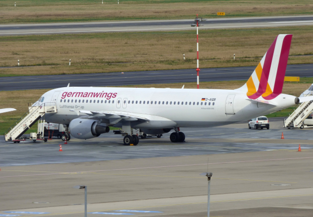 Germanwings Airbus A320-200 auf dem Frankfurt Airport geparkt mit Bodenfahrzeugen, Verkehrskegeln, Versorgungsmasten und Grasfläche im Hintergrund.