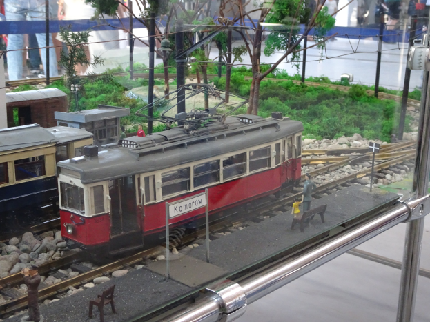 Ein Modellzug in einer Glasvitrine mit Miniatur-Eisenbahnlandschaft und Zuschauern