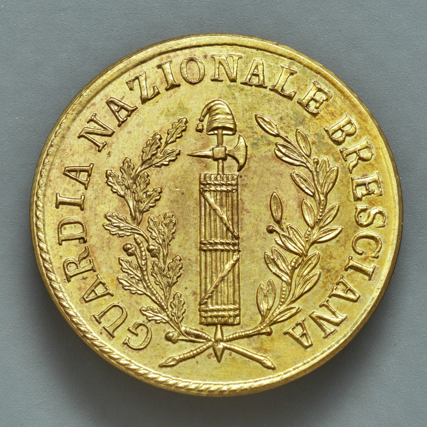 Eine Goldmünze mit der Aufschrift "Guardia Nazionale Brescia" auf einem grauen Hintergrund.