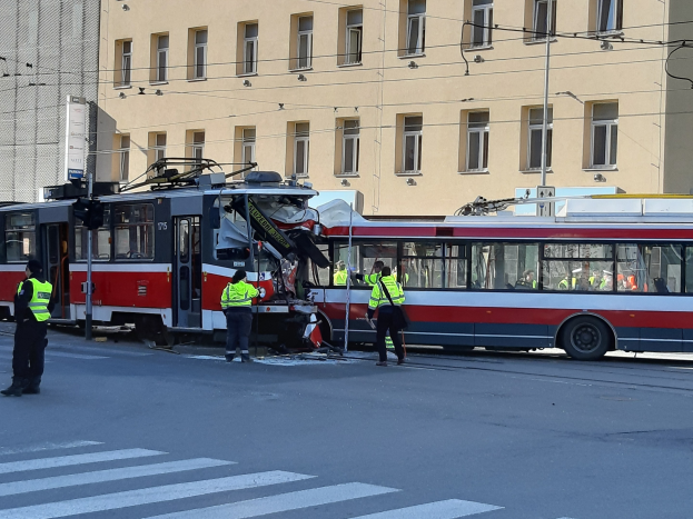 Rote und weiße Straßenbahn krachte auf der Straße mit einigen Menschen in der Nähe und einem Gebäude im Hintergrund.