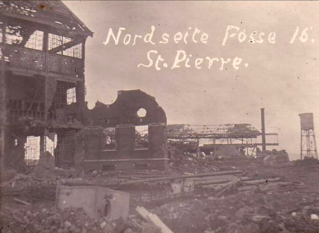 Ein Schwarz-Weiß-Foto eines zerstörten Gebäudes mit einem Turm auf der rechten Seite, kaputten Fenstern und Schutt in der Umgebung.