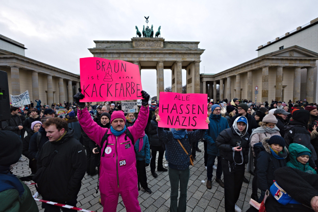 Gruppe von Menschen protestiert vor dem Brandenburger Tor in Berlin und hält Schilder gegen die Anti-Nazis-Bewegung der deutschen Regierung.