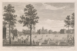 Eine Gruppe von Menschen, die während eines Umzugs im St. James Park stehen und sitzen, mit Bäumen und Gebäuden im Hintergrund unter einem bewölkten Himmel.