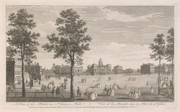 Eine Gruppe von Menschen, die während eines Umzugs im St. James Park stehen und sitzen, mit Bäumen und Gebäuden im Hintergrund unter einem bewölkten Himmel.