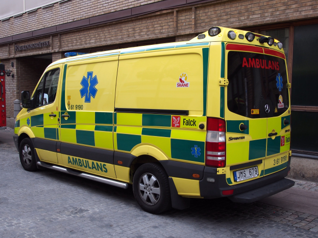 Ambulanz auf der Straße vor einem Backsteingebäude mit Text geparkt, mit einem Feuerlöscher auf der linken Seite sichtbar.