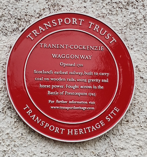 Ein rundes rotes Schild an einem Gebäude mit der Aufschrift "Transport Trust".