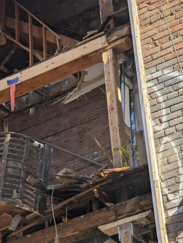 Teilweise abgerissenes Gebäude mit verstreuten Holzplanken und Trümmern, gebrochene Fenster und Türen nach einer Abriss.