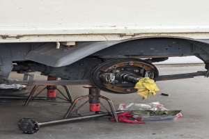 Ein gelber, mit einem Tuch bedeckter Lkw in einer Garage mit Werkzeugen und Gegenständen, die vor ihm auf dem Boden verstreut sind.