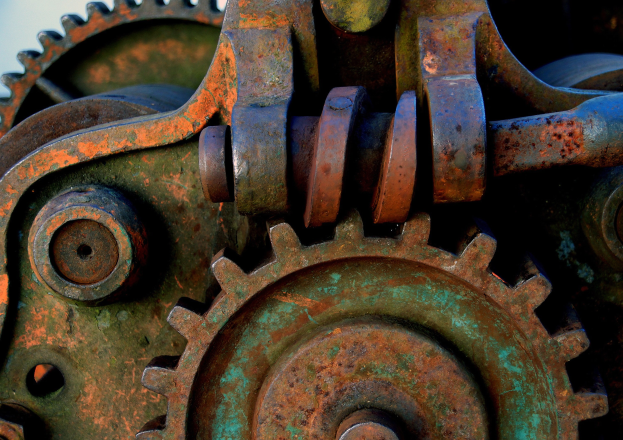 Nahaufnahme eines verrosteten Metallzahnrads mit mehreren Zahnrädern und Zähnen, das Zeichen von Alter und Abnutzung gegen einen unscharfen Hintergrund zeigt.