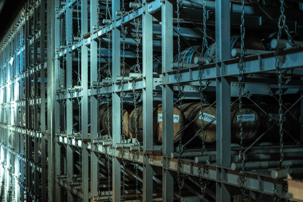 Großlager mit zahlreichen Fässern in ordentlichen Metallregalen verbunden durch Stangen und Ketten.