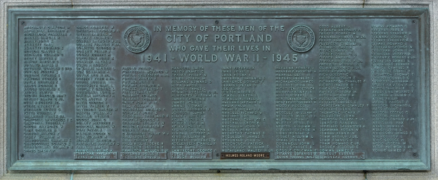Metallplakette an einer Gebäudewand mit "Denkmal für die Stadt Portland" in fetter schwarzer Schrift, umgeben von einem dekorativen Rahmen.