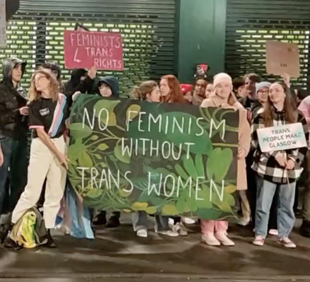 Eine Gruppe Von Menschen Hält Ein Banner Mit Der Aufschrift 'Kein Feminismus Ohne Trans-Frauen' Und Schilder In Einer Öffentlichen Fläche.